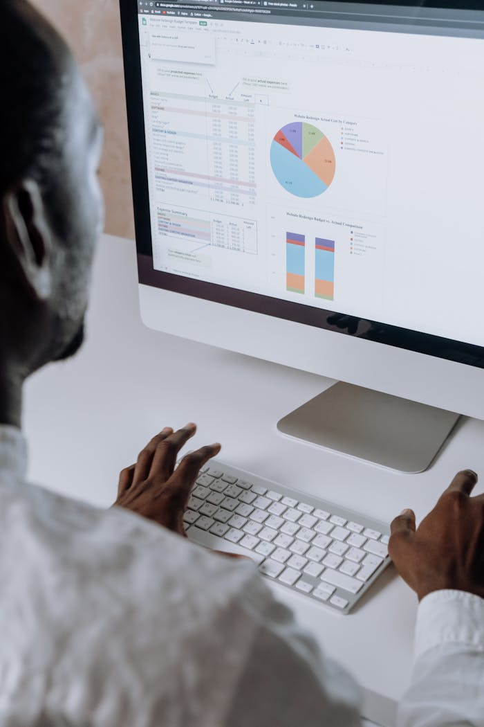 Services Businessman analyzing charts and data on desktop computer in office setting.