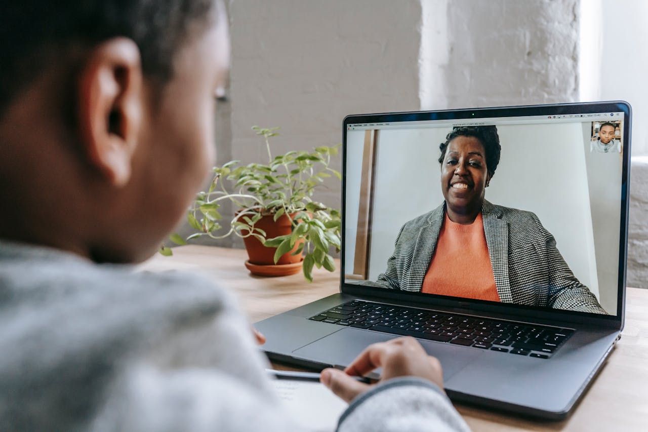 Crafting Captivating Headlines: Your awesome post title goes here A child engages in a remote learning session with a woman via video call on a laptop.