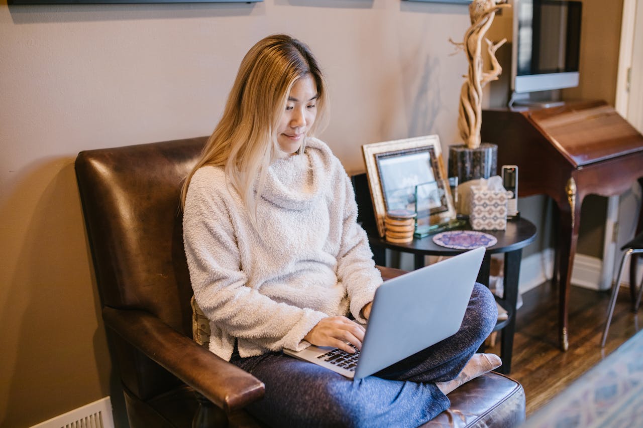 The Art of Drawing Readers In: Your attractive post title goes here Woman seated on a chair using a laptop, enjoying a cozy home office environment.