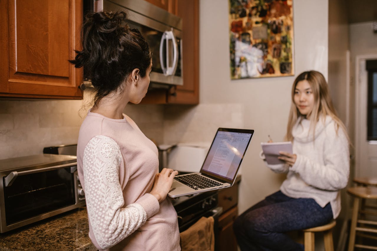 Mastering the First Impression: Your intriguing post title goes here Two women collaborate on laptops and notes in a cozy home kitchen setting.